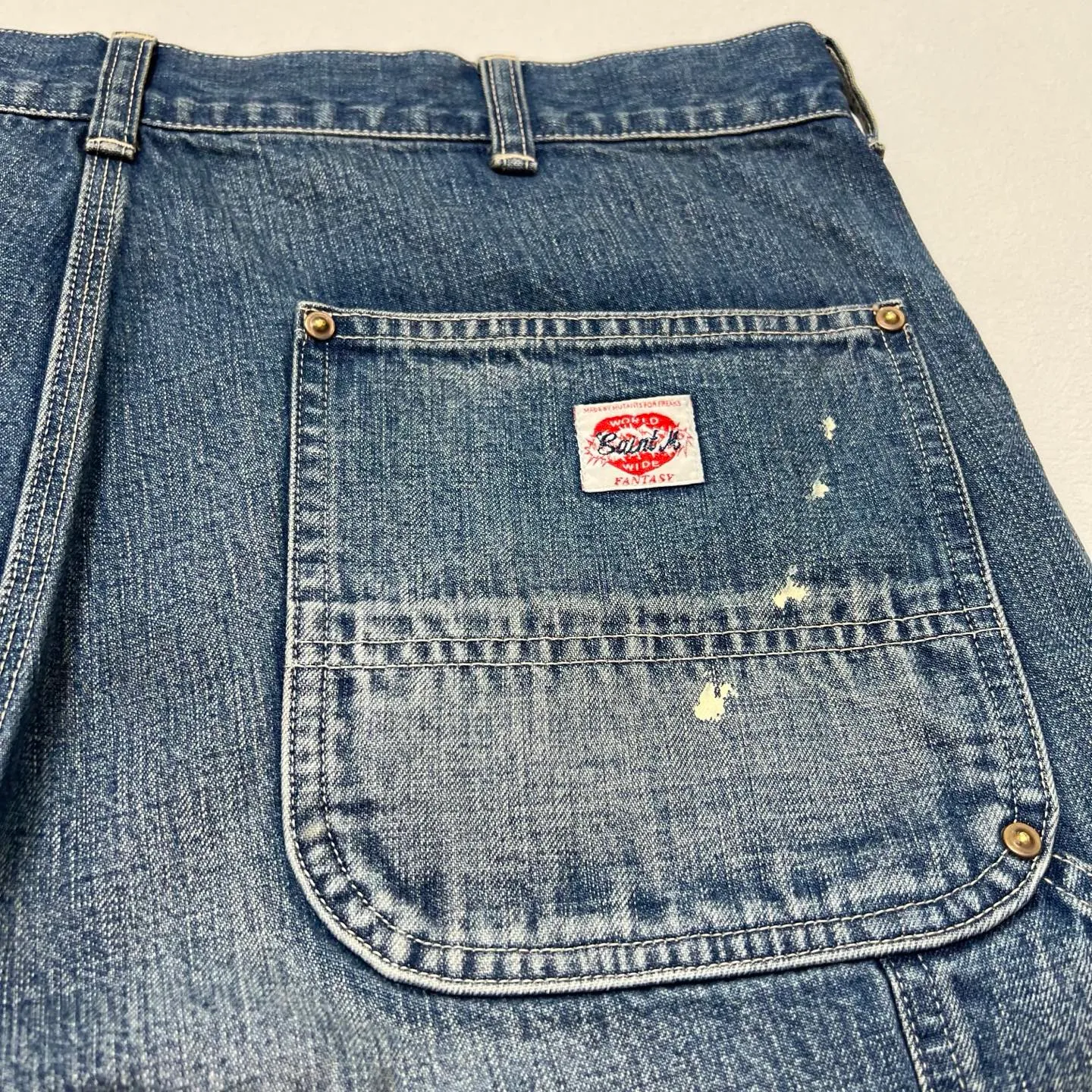 SAINT Mxxxxxx DOUBLE KNEE SHORTS/BLU Knee patches splashed with ink and water-splashed denim shorts. Denim blue S-XL. Custom-woven and dyed denim fabric with clear texture. Heavy-wash water-fading treatment to create local mottled fading/hole effects. Artificial distressing to simulate natural wearing marks. VINTAGE sense. Original consistent damage treatment. Hand-splashed ink and paint. Original consistent wash mark/pocket mark. Double knee patch. Rivet reinforcement. Improve functionality while enhancing design